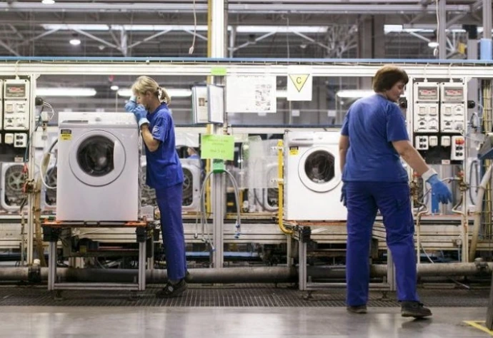lavadoras blancas en fabricación con operarios